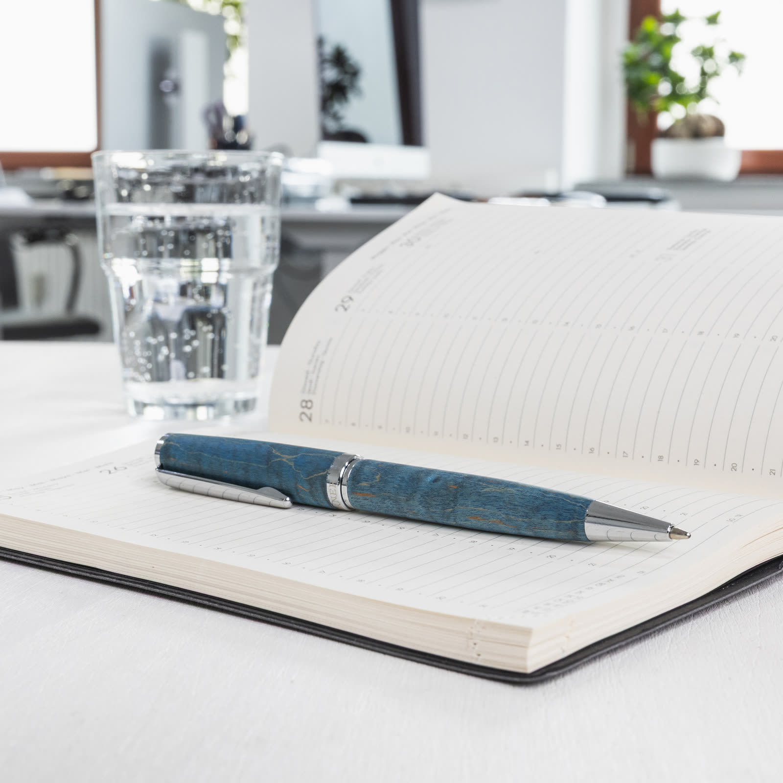 Hörner Primus Oceanus Schreibgerät mit blauer Holzmaserung auf einem aufgeschlagenen Notizbuch in heller Büro-Umgebung