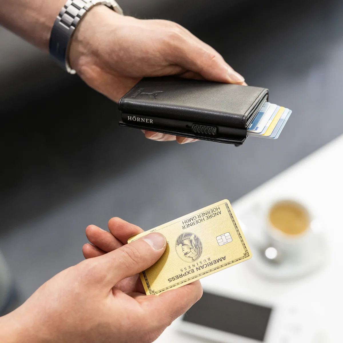 Nahaufnahme des Hörner Nexus Slim Wallet, eine Hand zieht eine Karte aus dem gestaffelt aufgefächerten Pop-Up-Kartenfach
