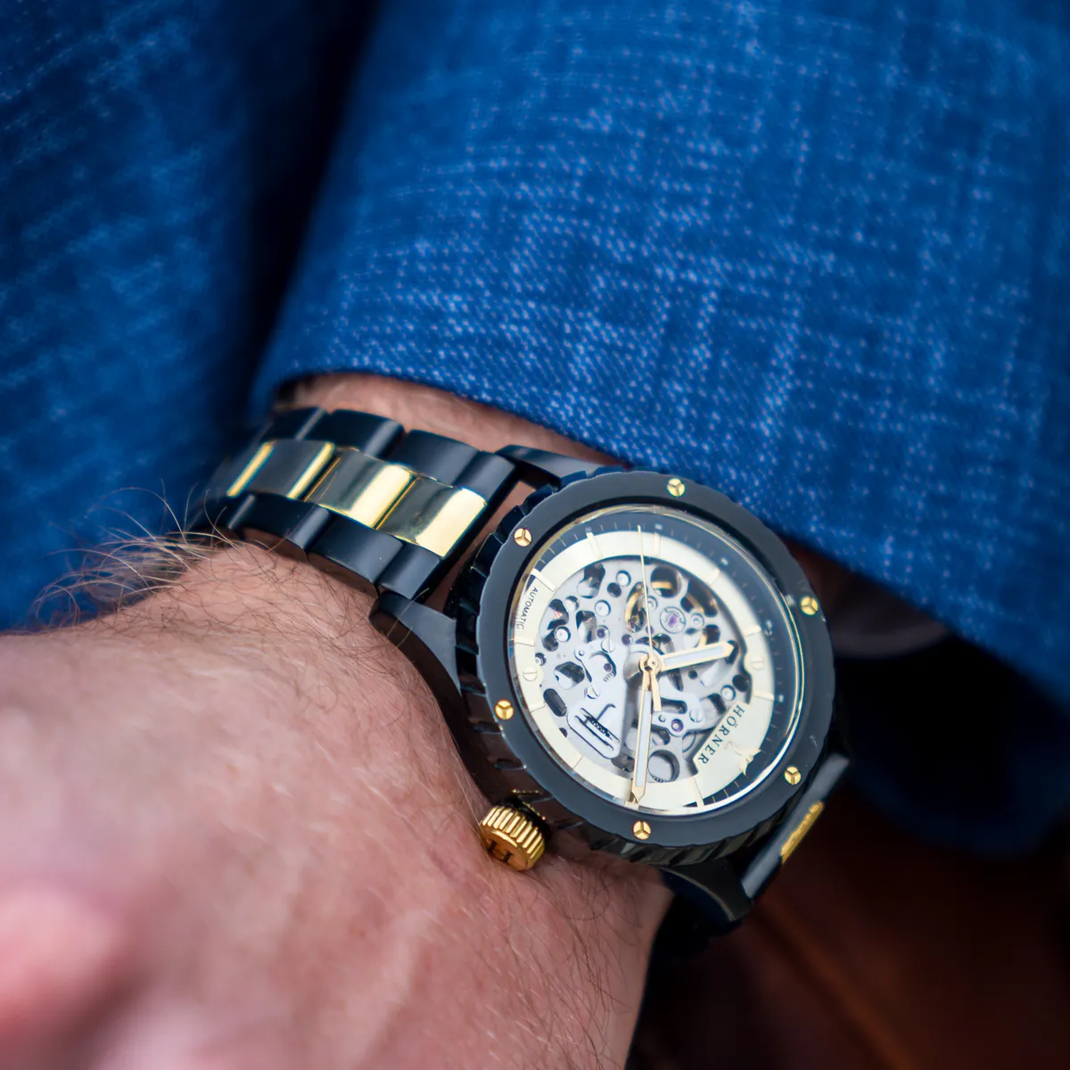 Hörner Pulsar Imperial Automatikuhr mit skelettiertem Zifferblatt am Handgelenk, im Hintergrund ein blauer Sakko-Ärmel und eine braune Ledertasche