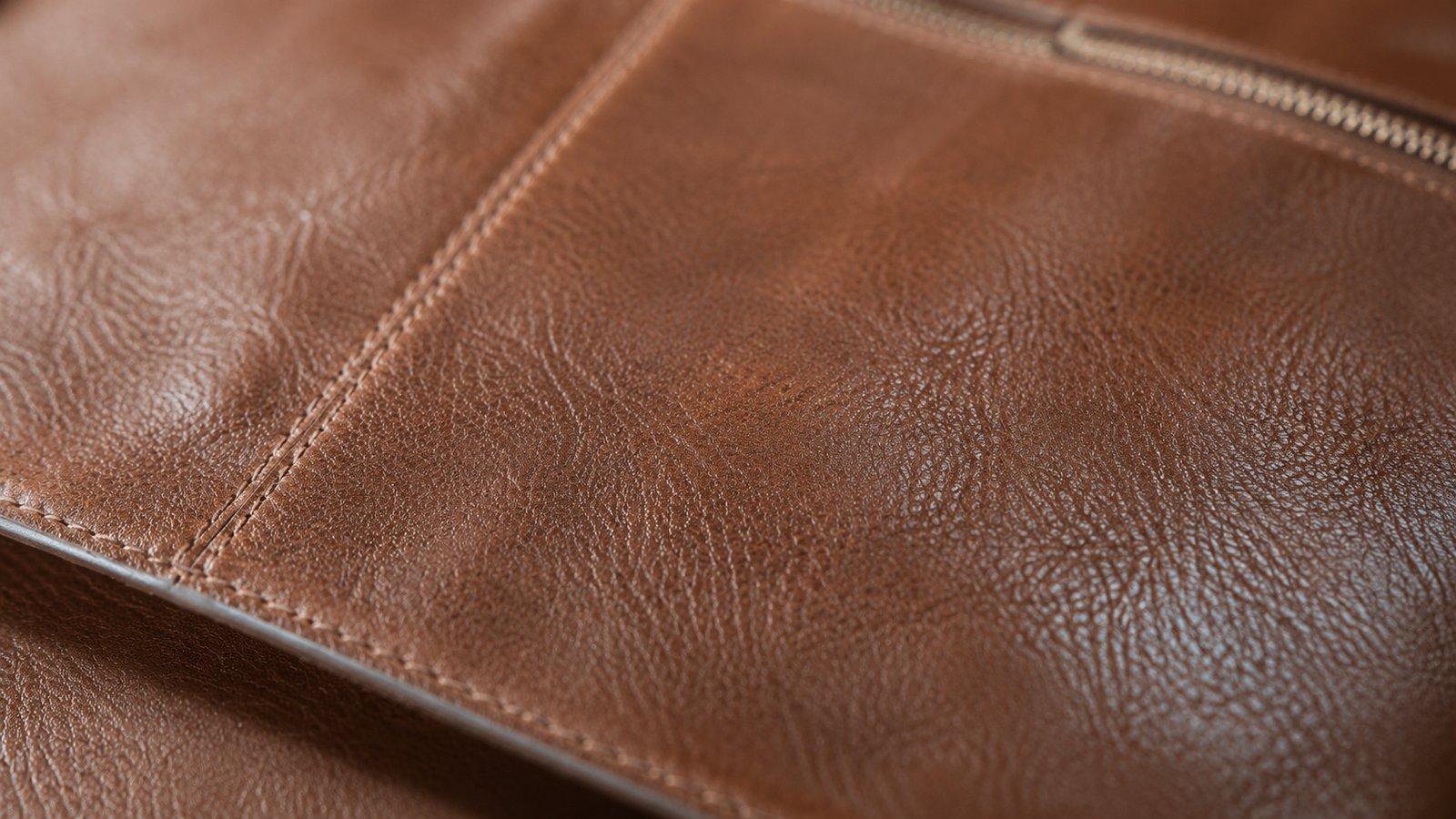Cognac-farbenes Vollleder mit charakteristischer Patina, sichtbare Gebrauchsspuren entlang der Nähte und Falten